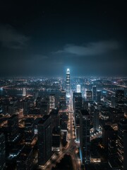 Fototapeta premium An aerial shot of skyscrapers and streets. It is night time. Some clouds are visible in the sky above them. A body of water can be seen on one side too..