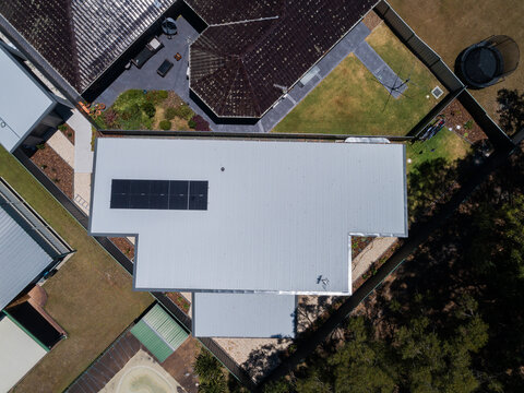 Aerial view of house in small lot of land with newly installed mini solar system on roof of house