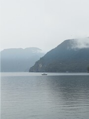 Boats in water with mountains and mist.