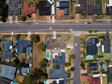 Sunlit street in suburbs with t intersection and houses alongside road