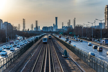Fototapeta premium Metro trains and vehicles at dusk in Beijing, China