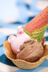 Close-up balls of chocolate and raspberry ice cream in a waffle bowl decorated with a brightly...