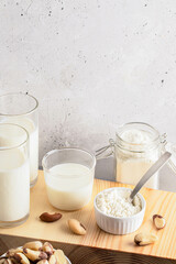 Brazil nut milk and flour are beautifully arranged in glass jars on a wooden board, accompanied by whole nuts, set against a soft, neutral background, showcasing natural food products