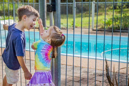 Brother and sister being silly outside pool gate