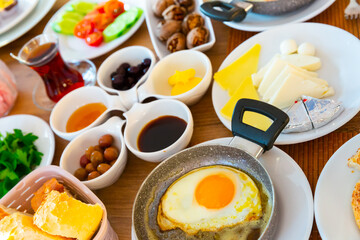 Traditional halal breakfast with various cheeses, green and black olives, bread, eggs, fresh vegetables and walnuts served at Turkish hotel.