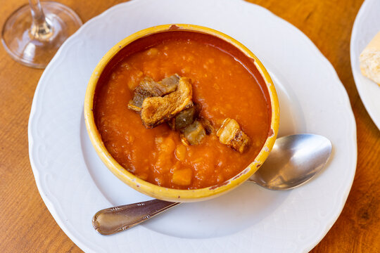 Patatas meneas, traditional Spanish dish made of mashed potatoes and torreznos, crispy bacon strips, served in bowl.