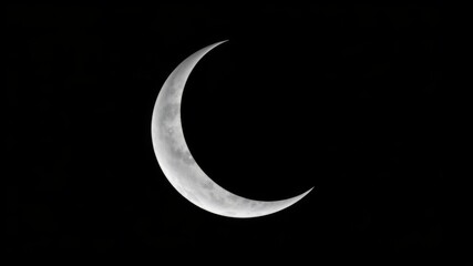 Obraz premium A crescent moon shines brightly in the inky black night sky showcasing its detailed craters and subtle texture.