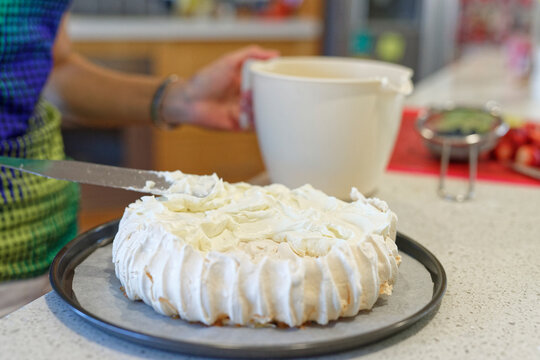 Woman spreading the cream onto the traditional Australian Pavlova