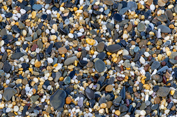Close up image of small colorful pebbles and stones on a beach.