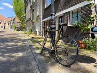 Fototapeta premium Bicycle parked on sidewalk in front of brickwall building in Delfshaven. Biking in Holland