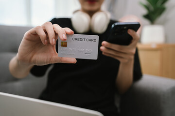 A woman shops online at home using her laptop, holding a credit card while making a secure e-commerce payment in comfort.