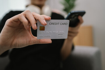 A woman shops online at home using her laptop, holding a credit card while making a secure e-commerce payment in comfort.