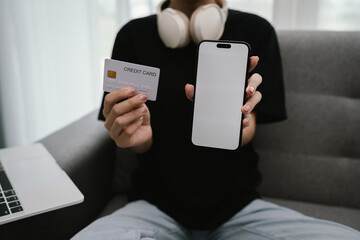 A woman shops online at home using her laptop, holding a credit card while making a secure e-commerce payment in comfort.