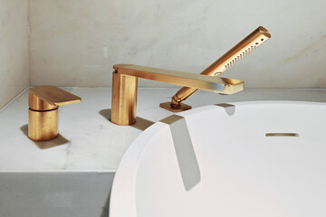 A stylish brass faucet set complements a minimalist bathtub in a luxurious bathroom setting
