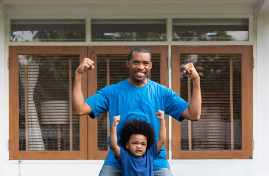 African American father and his son are joyfully posing with raised fists at outdoor, showcasing excitement and togetherness. Black Family celebrate strength while making playful poses