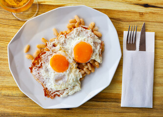 Appetizing fried eggs with stewed white beans. Traditional Catalan breakfast