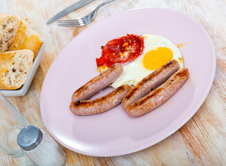 Appetizing grilled sausages served with fried eggs and tomato