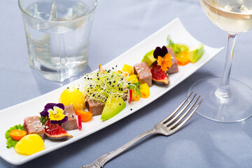 Tasty pan seared tuna served on white plate with avocado, mango and figs garnished with greens and pansy flowers