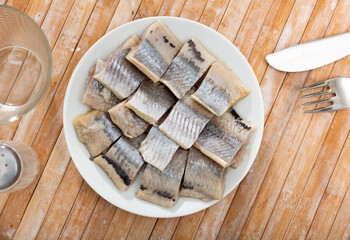 Fillet of appetizing herring, laid out on a plate. Close-up image
