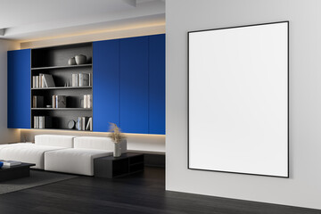 Modern interior with blank vertical poster frame on wall next to white sofa and bookshelf with blue panels in clean minimal living room layout. 3D Rendering