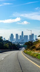 Obraz premium Scenic Highway View of City Skyline Under Bright Blue Sky