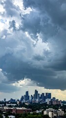 Fototapeta premium Dramatic City Skyline Under Turbulent Sky with Dark Clouds