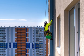 Rope access specialist washes the facade of a building