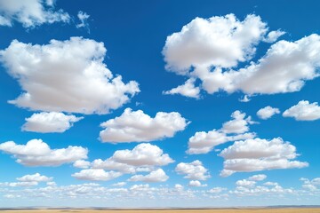 Vast expanse of a clear blue sky dotted with fluffy white clouds, above a flat, light brown landscape