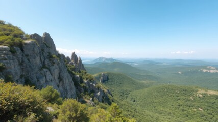 Fototapeta premium A breathtaking panoramic view of majestic rocky mountains and lush green valleys under a clear blue sky.