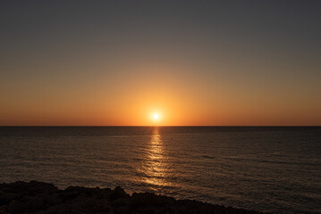 Sunrise or sunset over the sea with calm waters.