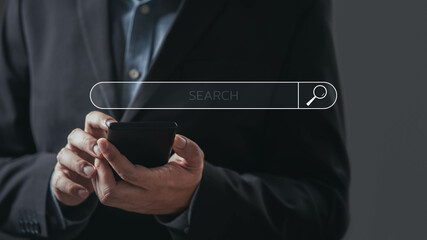 A professional person in a suit is using a smartphone with a search bar overlay, suggesting research or online inquiries.