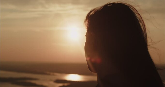 Young woman watching golden sunset over river