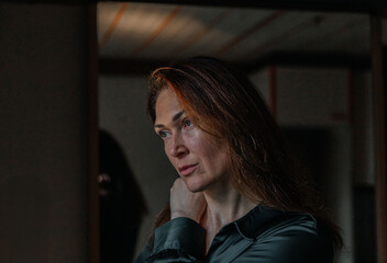 Pensive caucasian female in green shirt with long brown hair and intense gaze