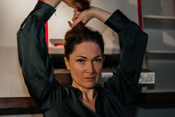 Caucasian female adult adjusting hair indoors in dimly lit room