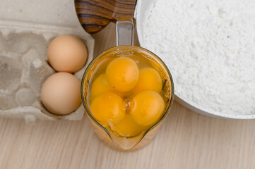 Rozbite jajka w szklanym dzbanku obok miska z mąką domowe pieczone ciasta, świeże kurze jaja © Paweł Kacperek