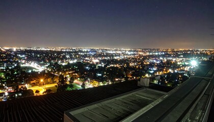 Naklejka premium Rooftop View of Cityscape at Night with Streetlights Illuminating Below