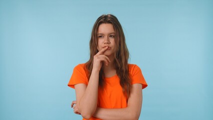 Woman in Orange Shirt Deep in Thought Against Blue Background