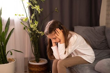 One sad girl is sitting on the couch at home. Child abuse. Anxiety and stress. Concept of bullying, depression, stress or frustration, sadness. close-up.
