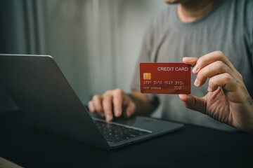 Close-up Man hand Holding Credit Card While Using Laptop for Online Transactions in Modern Setting,...