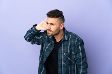 Caucasian man isolated on purple background listening to something by putting hand on the ear