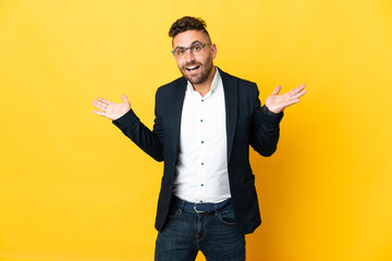 Businessman over isolated yellow background with shocked facial expression