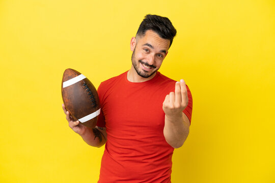 Young Caucasian man playing rugby isolated on yellow background making money gesture