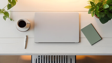 Laptop with coffee, pen, notebook and plant on a white wooden desk
