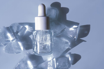 Transparent glass dropper bottle with white cap placed on melting ice cubes, captured in cool light...