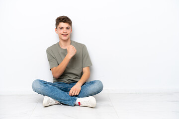 Fototapeta premium Teenager Russian man sitting on the floor isolated on white background celebrating a victory