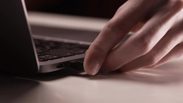 Close-up male hand turning-on type-c hub with cables in laptop.