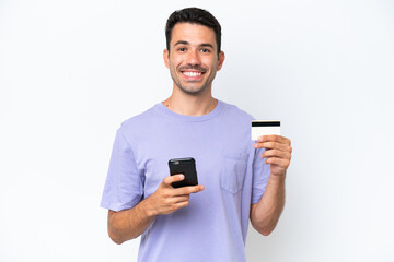 Young handsome man over isolated white background buying with the mobile with a credit card