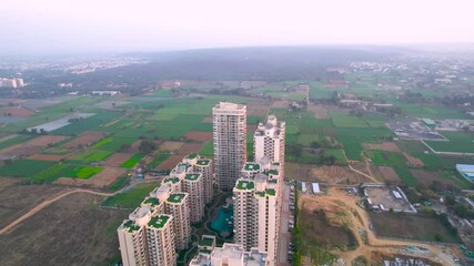 Aerial drone shot orbiting opulent high end multi story residential complex society with multiple towers and huge blue swimming pool in the middle showing the lavish living in Gurgaon Delhi