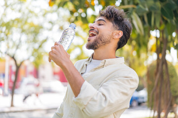 Young Arabian handsome man with a bottle of water at outdoors