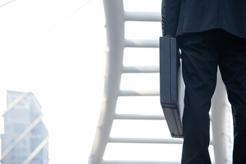 Close up hand holding business bag on the street. Unrecognizable businessman walking with a briefcase in a modern office. Business